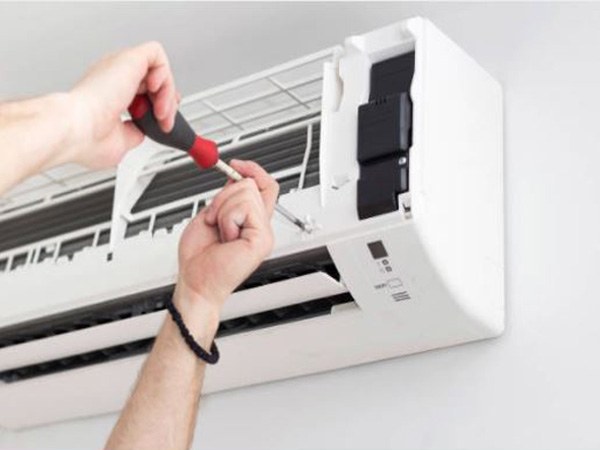 Hands fitting a wall-mounted air conditioning unit indoors