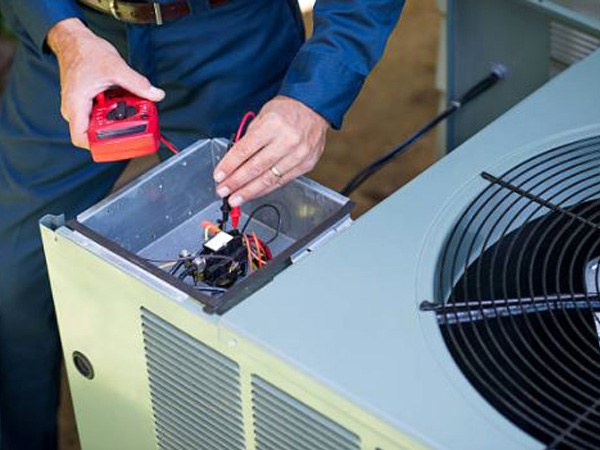 Technician servicing the top of an outdoor air conditioning unit