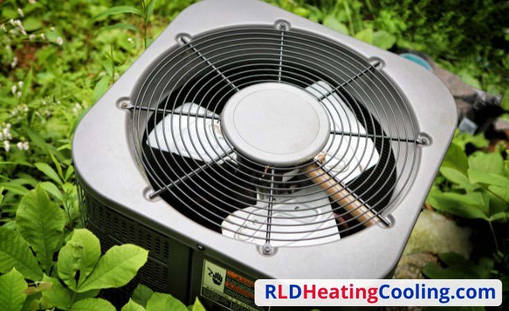 Close view of an outdoor condenser fan unit among greenery