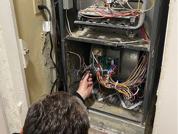 Technician working on the wiring inside a furnace