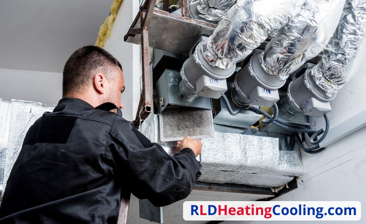 Technician working on insulated ductwork and piping